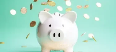 Piggybank surrounded by coins against a green background