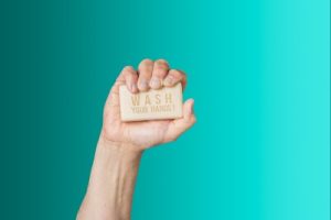 Hand holding hand soap against a blue background
