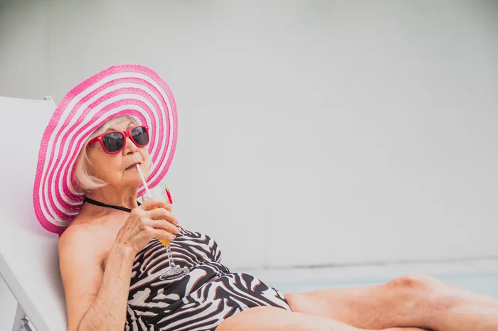 Older woman sunbathing with a pink hat and drink