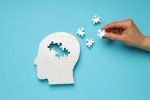 Jigsaw puzzle of a head with pieces missing against a blue background