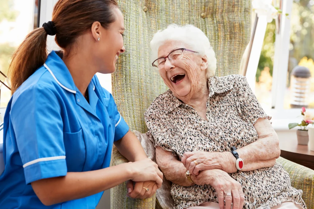 Elderly lady laughing with her carer