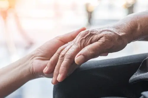 Close up of a younger person holding hands with an older person