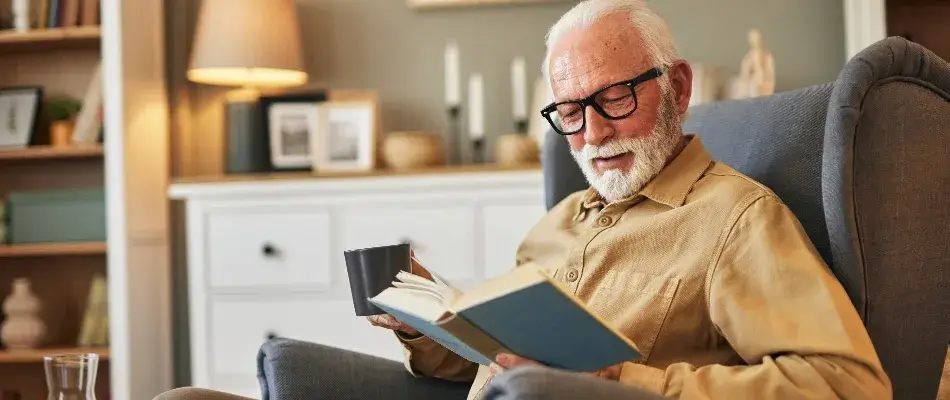 Older man with glasses reading in his chair