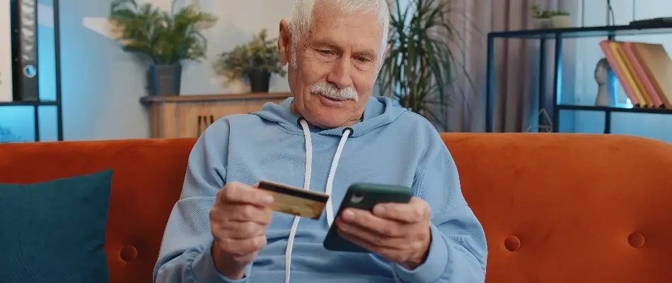 Older man in blue examining his credit card
