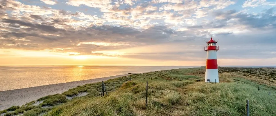 Red and white lighthouse on the coast at sunset